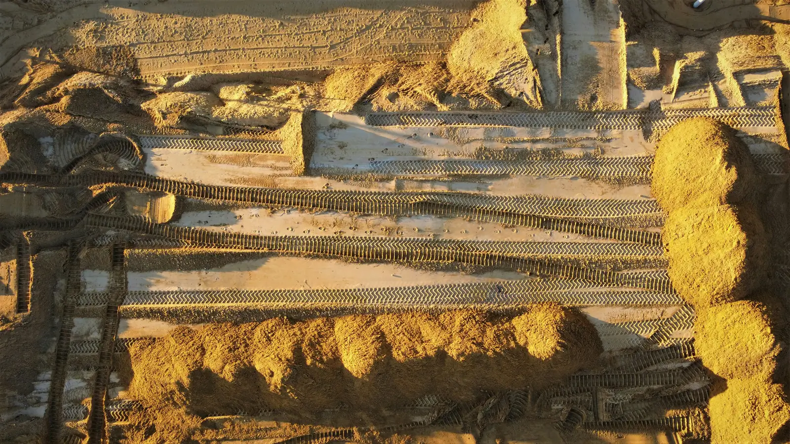 Vista cenital de un terreno en movimiento de tierra con huellas de maquinaria y montículos de material