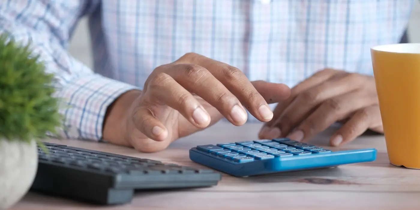 Manos trabajando en una calculadora junto al teclado