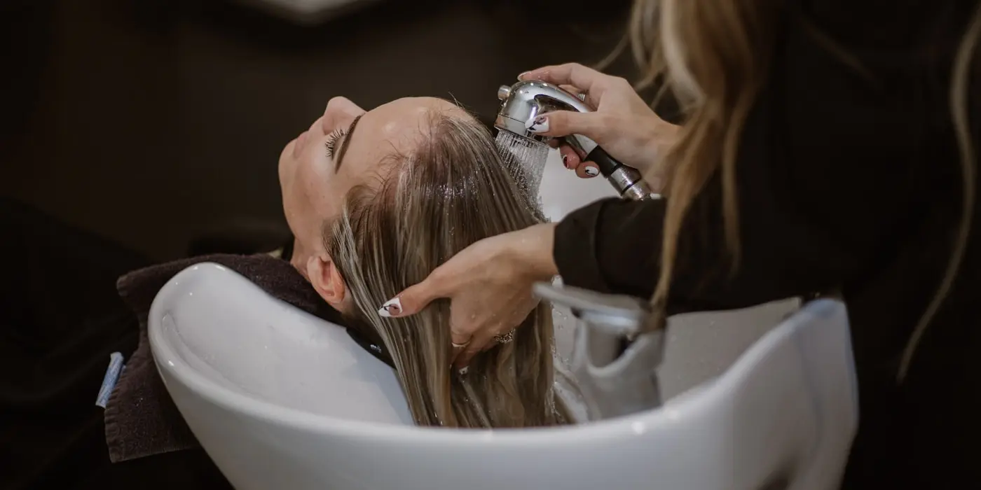 Una estilista lavando el cabello de una clienta en el salón