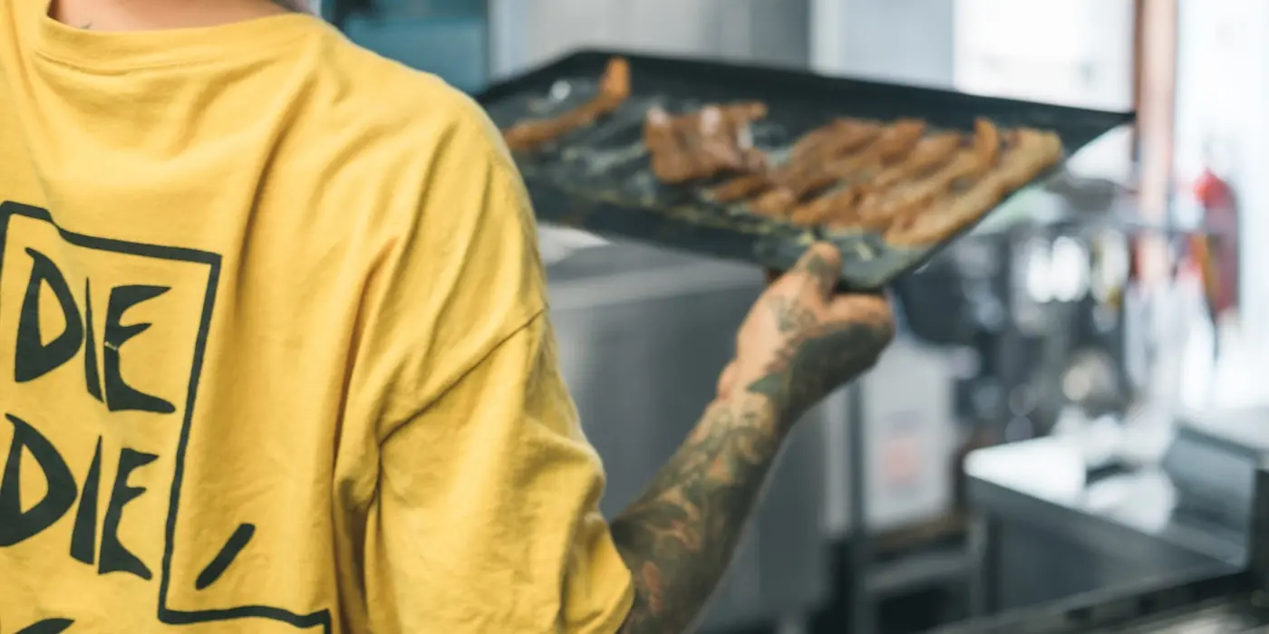 Un cocinero sacando una bandeja del horno durante el servicio